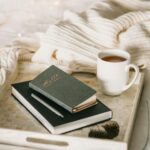 Relaxing setup with a cup of tea and journal on a bed, perfect for a cozy winter afternoon.